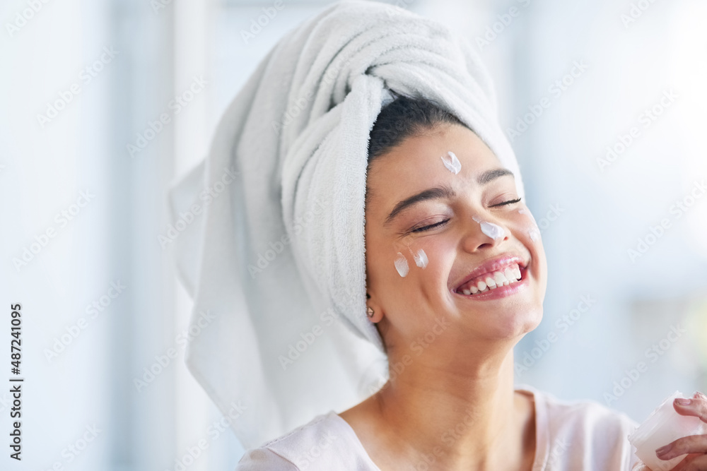 Not a wrinkle in sight. Shot of a beautiful young woman applying moisturizer to her skin in the bath