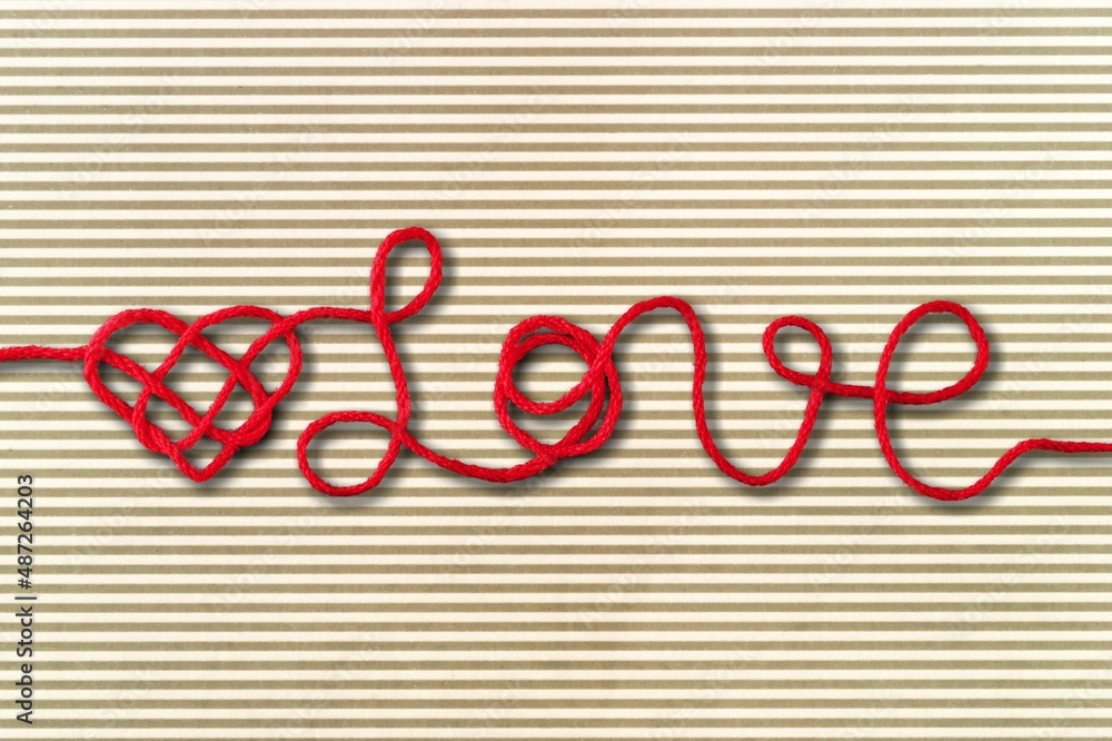 Colored rope in heart shape knot on background. Love concept.