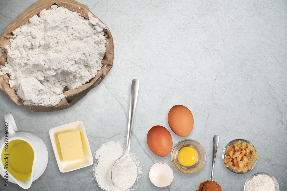 plate with wheat flour and ingredients for making dough for homemade cookies on a desk