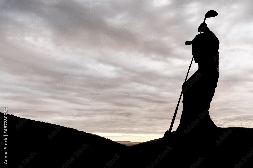 silhouette of a golfer swinging on sky background