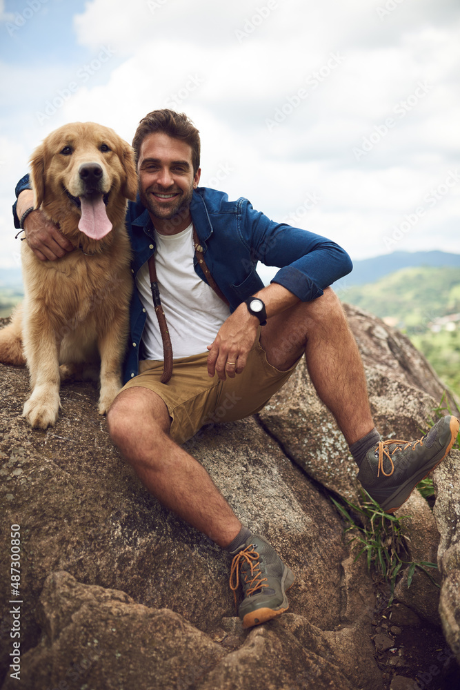 We made it to the top. Full length portrait of a handsome young man and his dog taking a break durin