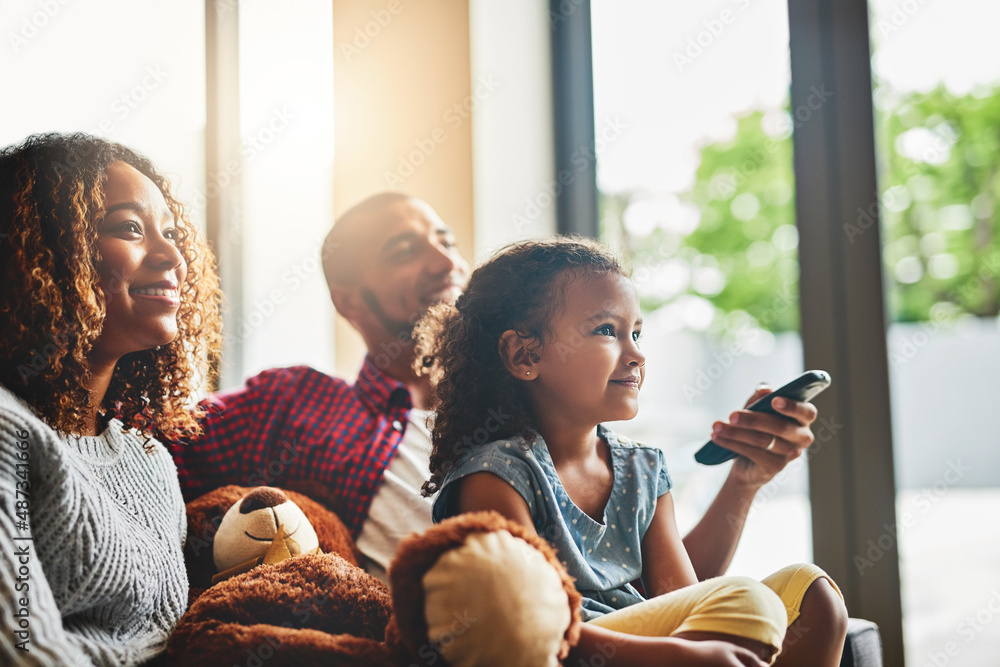 Weekends are about doing what everybody loves. Shot of a happy young family of three watching tv fro