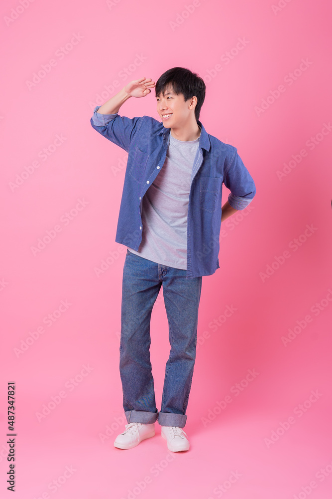 Young Asian man posing on pink background