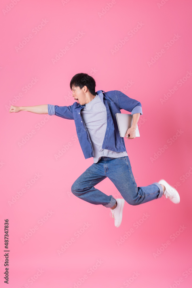 Young Asian man jumping on blue background