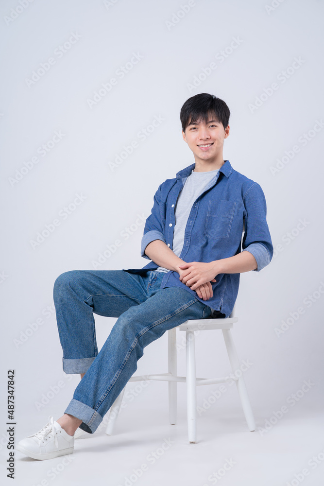 Young Asian man sitting on white background