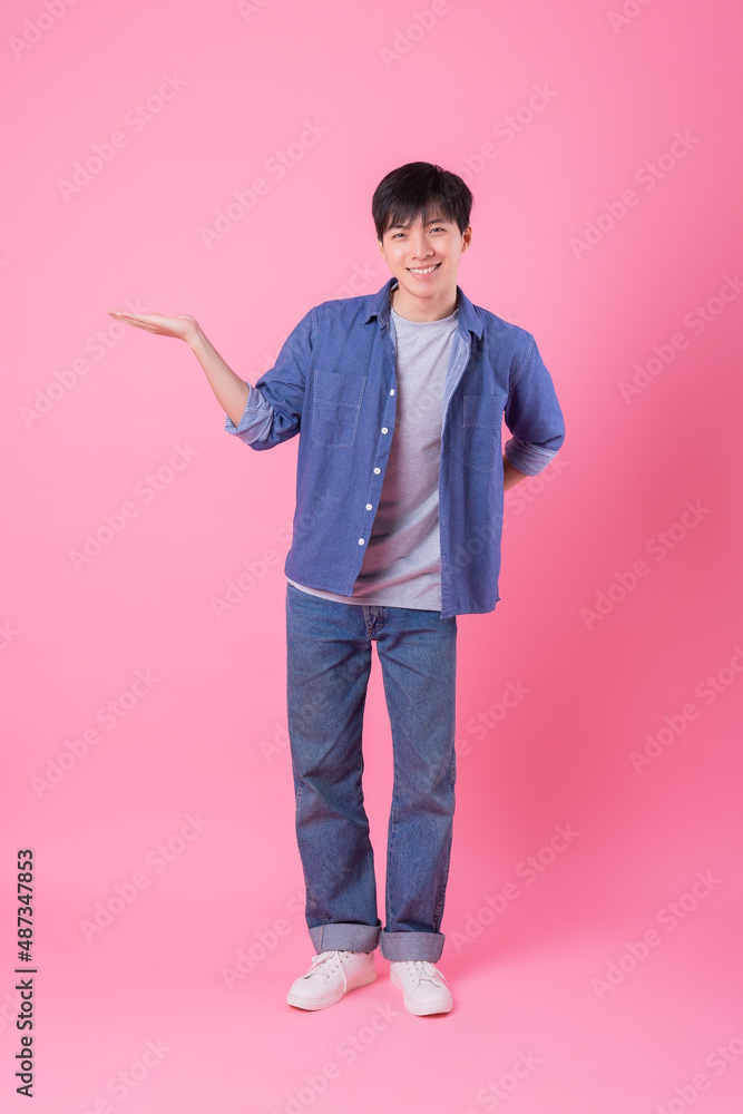 Young Asian man posing on pink background