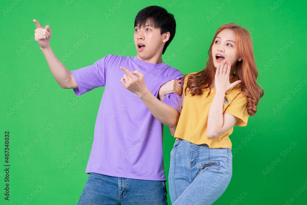 Young Asian couple posing on green background