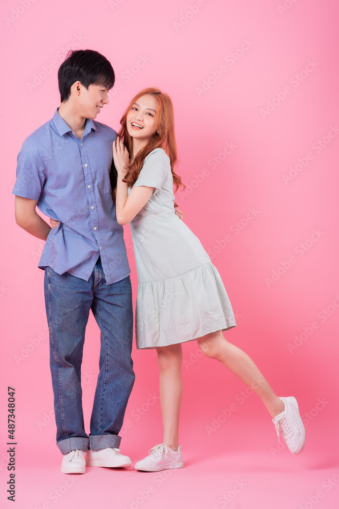 Young Asian couple posing on pink background