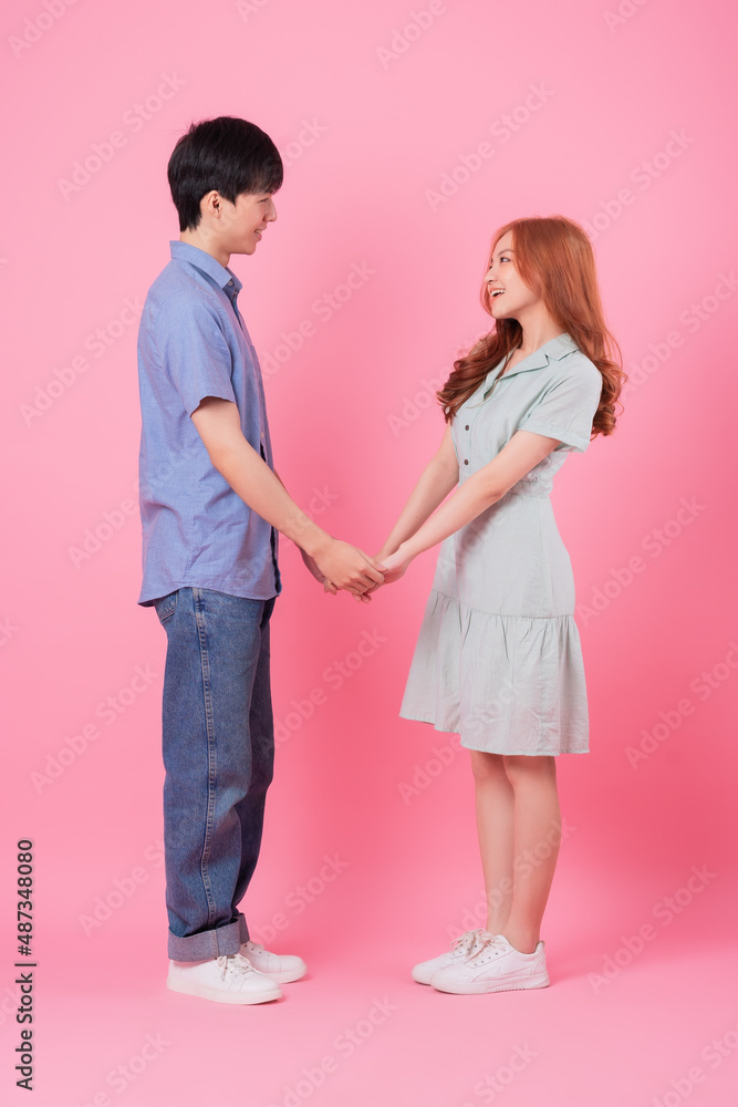 Young Asian couple posing on pink background