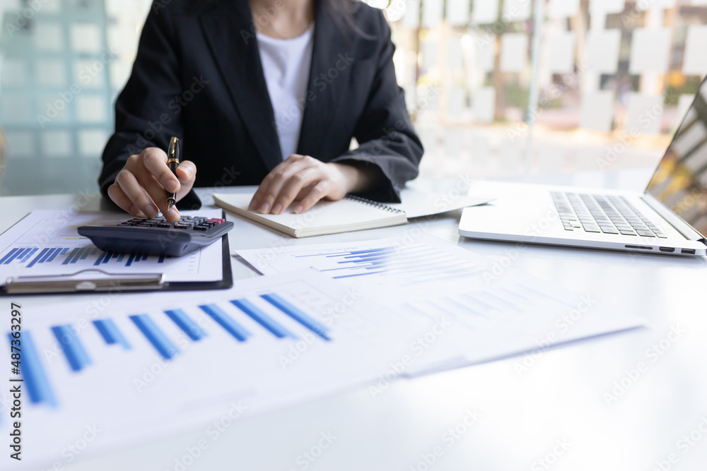 Businesswoman working on her desk using a calculator to calculate income and expenses to manage a bu