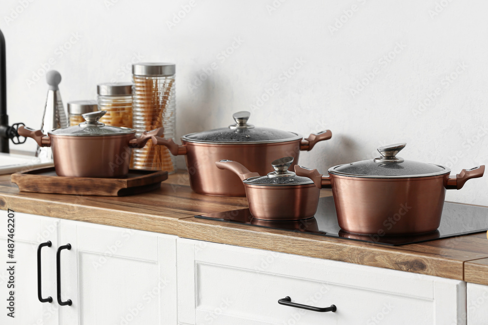 Shiny copper cooking pots on stove in kitchen