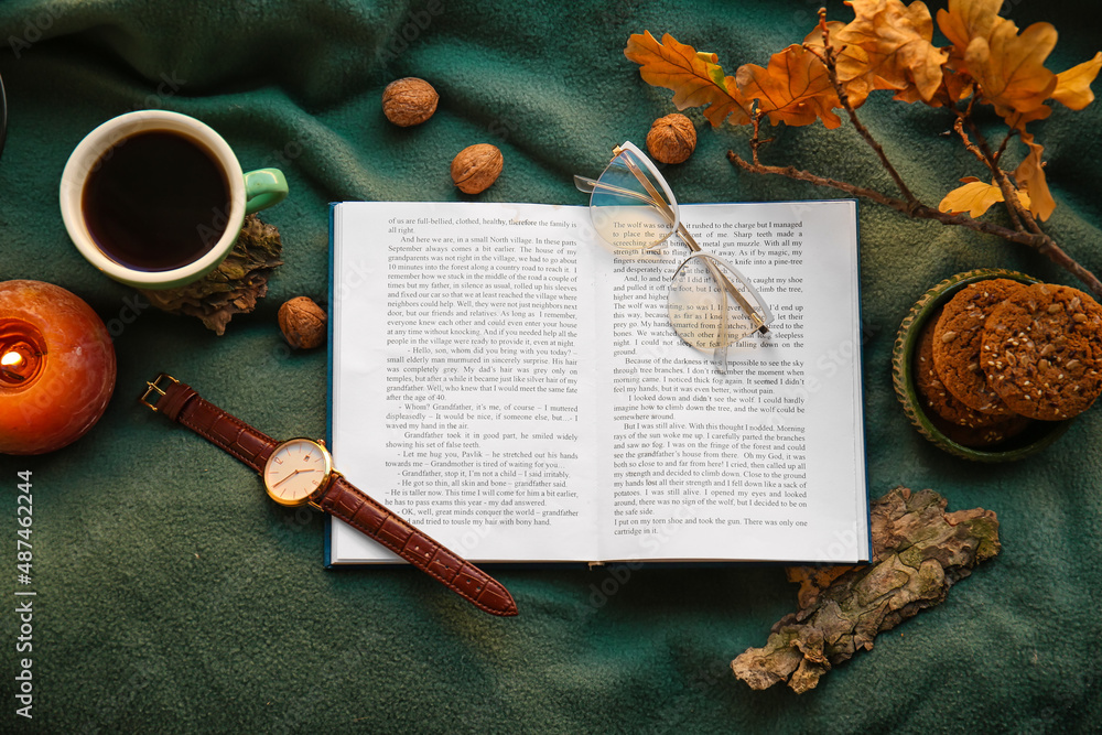 Book, eyeglasses, cup of coffee and autumn decor on plaid