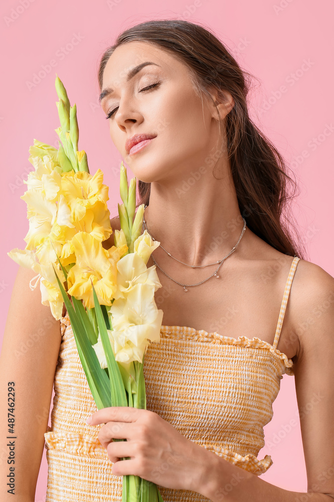 Beautiful young woman with closed eyes and bouquet of Gladiolus flowers on color background