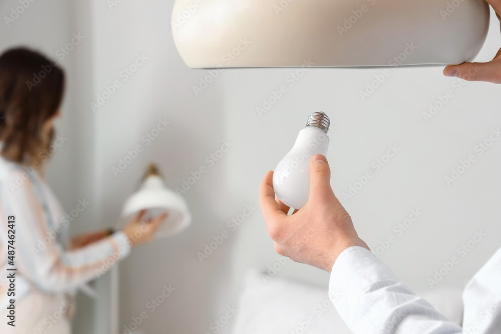 Man changing light bulb in hanging lamp at home, closeup