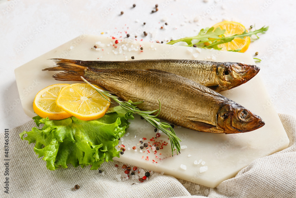 Board with smoked herring fishes on white background