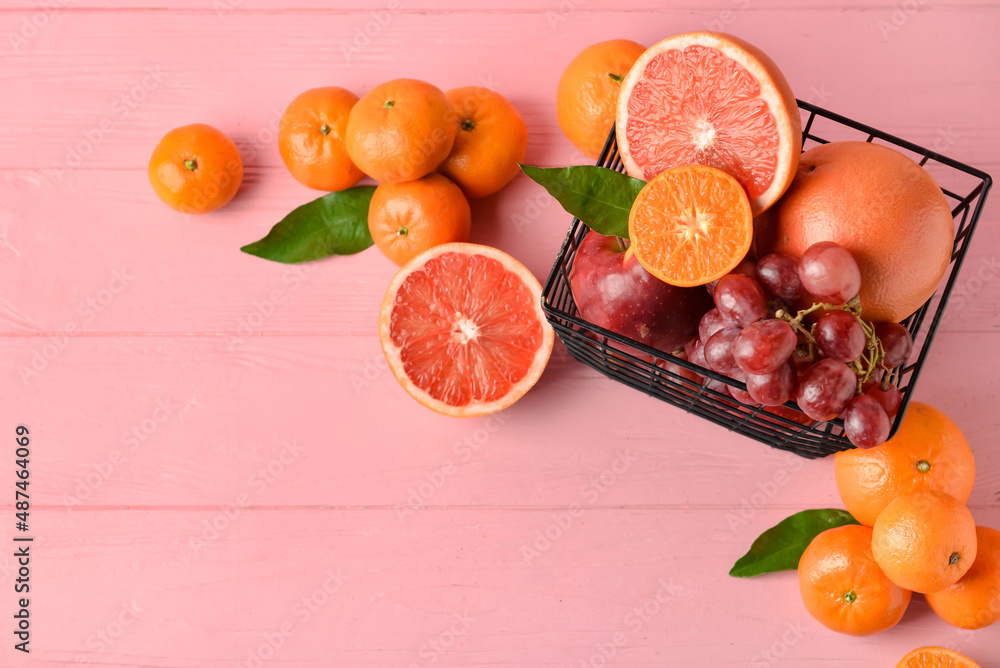 Basket with fresh juicy fruits on color wooden background