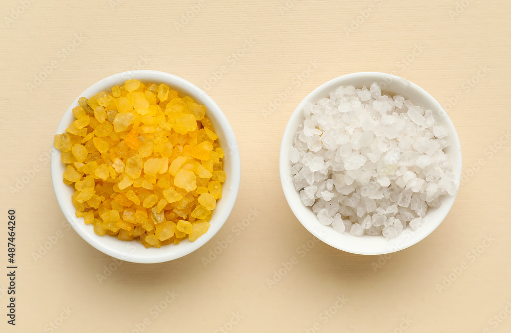 Bowls of different sea salt on color background