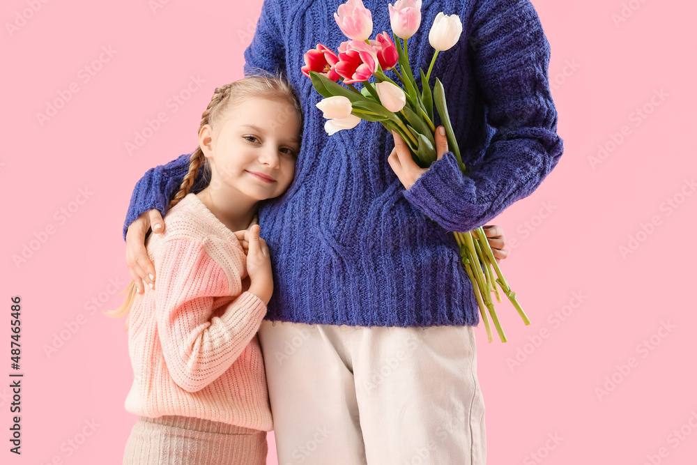 Little girl and her mother with tulip flowers on pink background