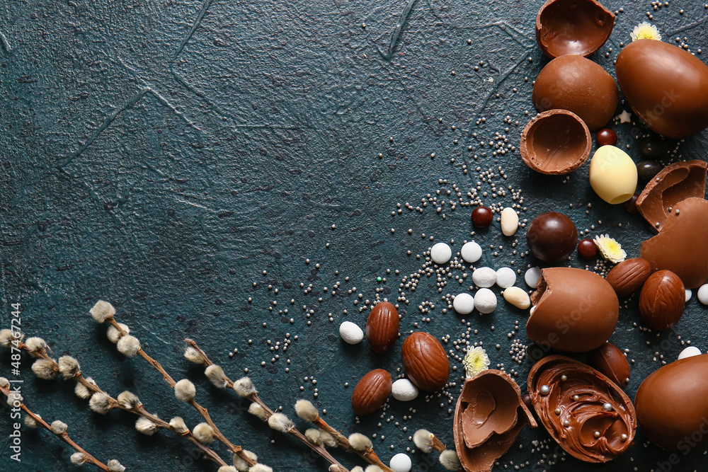 Composition with chocolate Easter eggs, candies and pussy willow branches on dark background