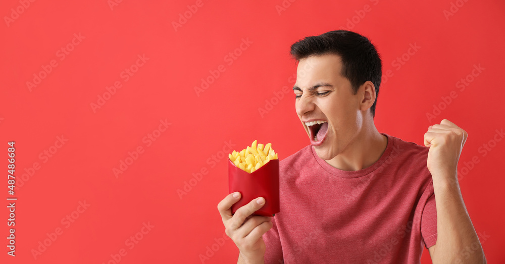 Emotional young man with french fries on red background