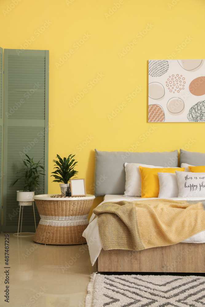 Stylish interior of modern bedroom with yellow wall