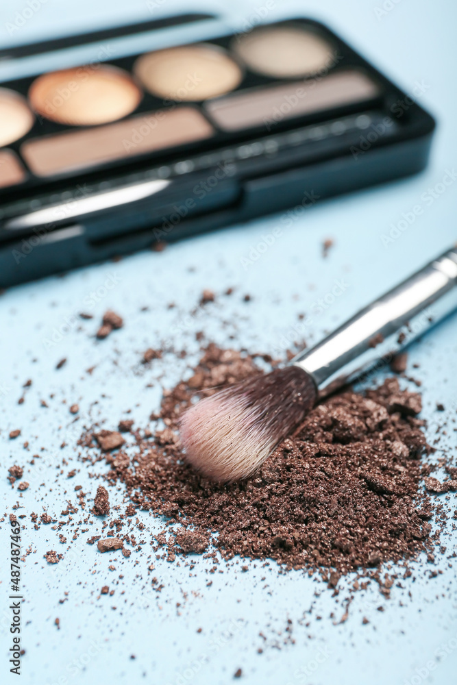 Makeup brush and loose eye shadow on color background