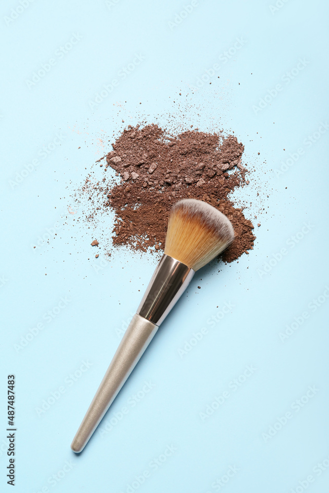 Makeup brush and loose eye shadow on color background