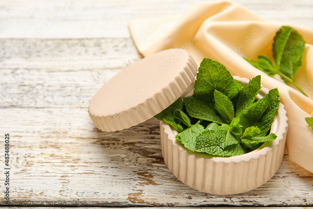 Box with mint leaves and napkin on wooden background