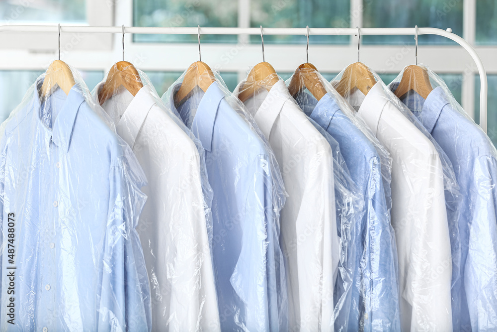 Rack with clean shirts in plastic bags after dry-cleaning