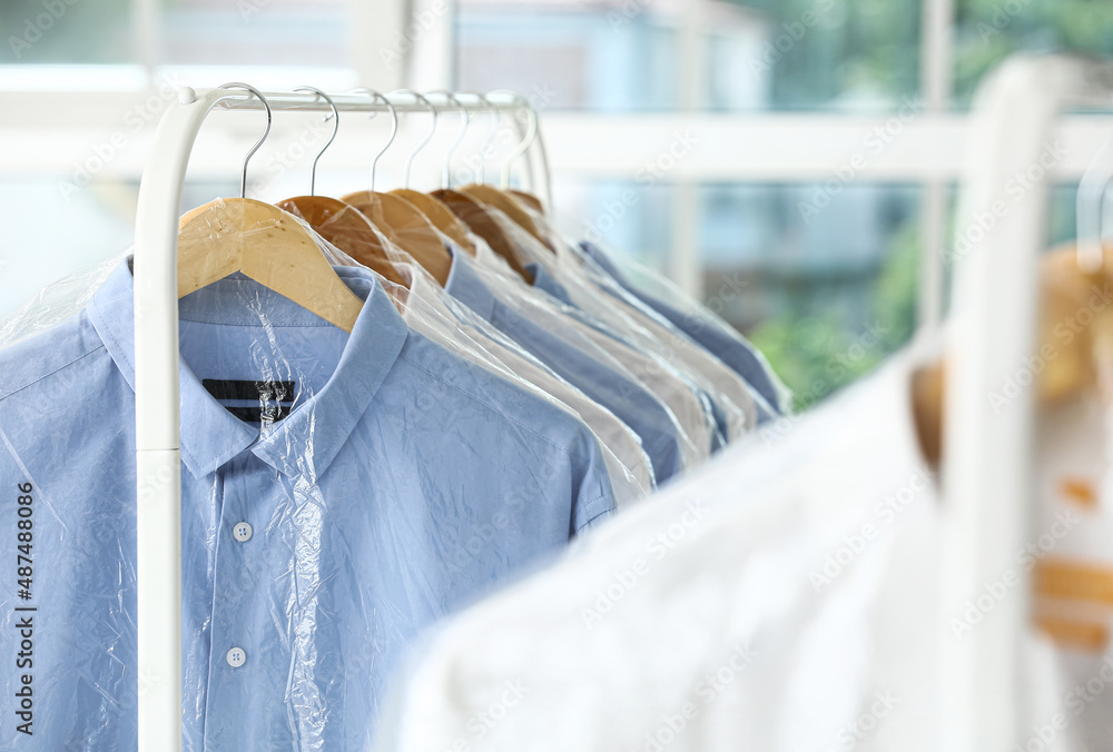 Rack with clean shirts in plastic bags after dry-cleaning