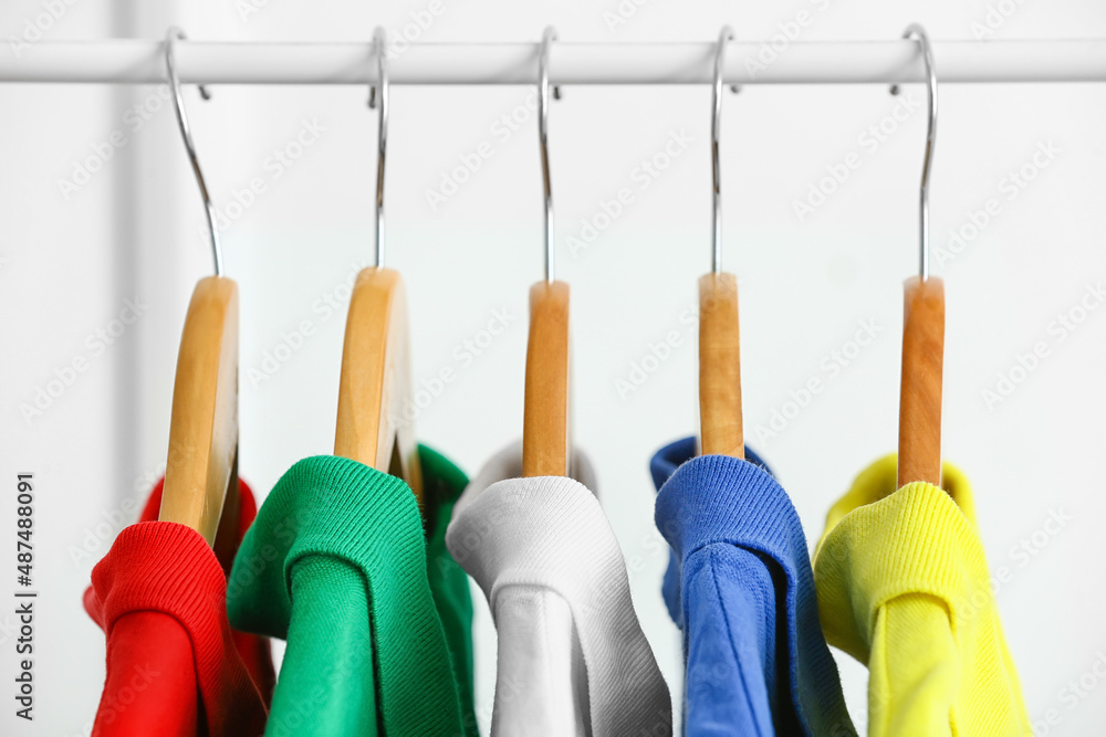 Rack with clean t-shirts near light wall