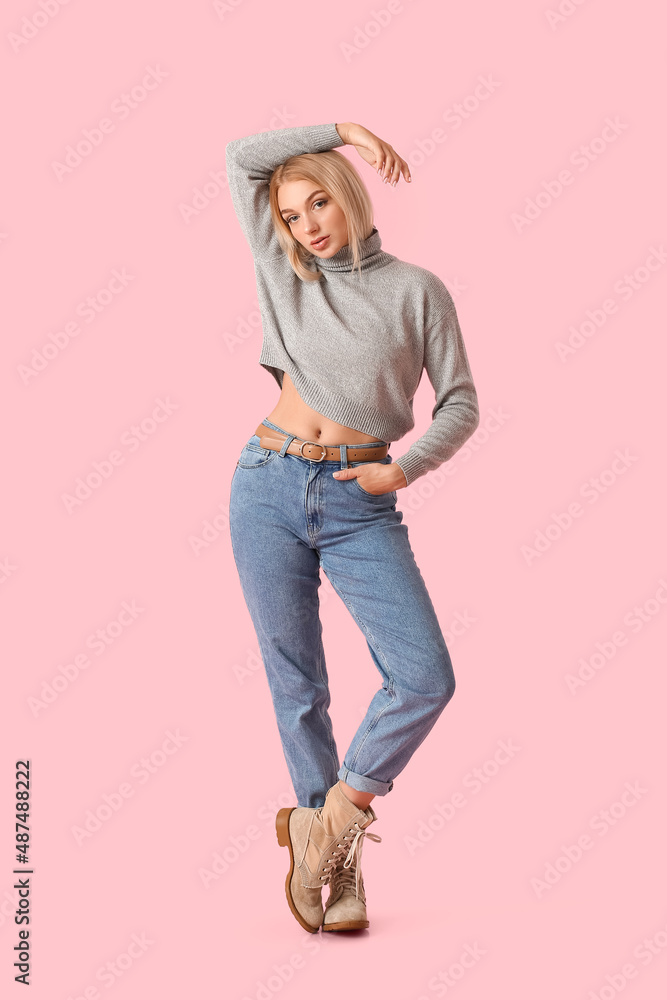 Fashionable young woman in stylish jeans on color background