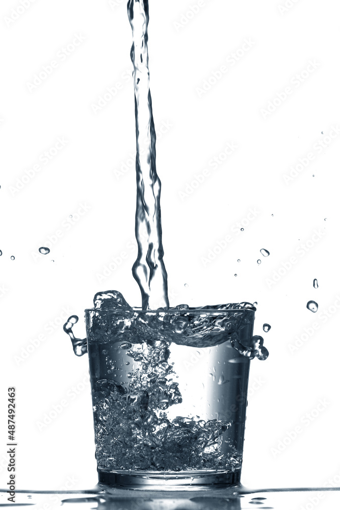 Pouring of clear water in glass isolated on white