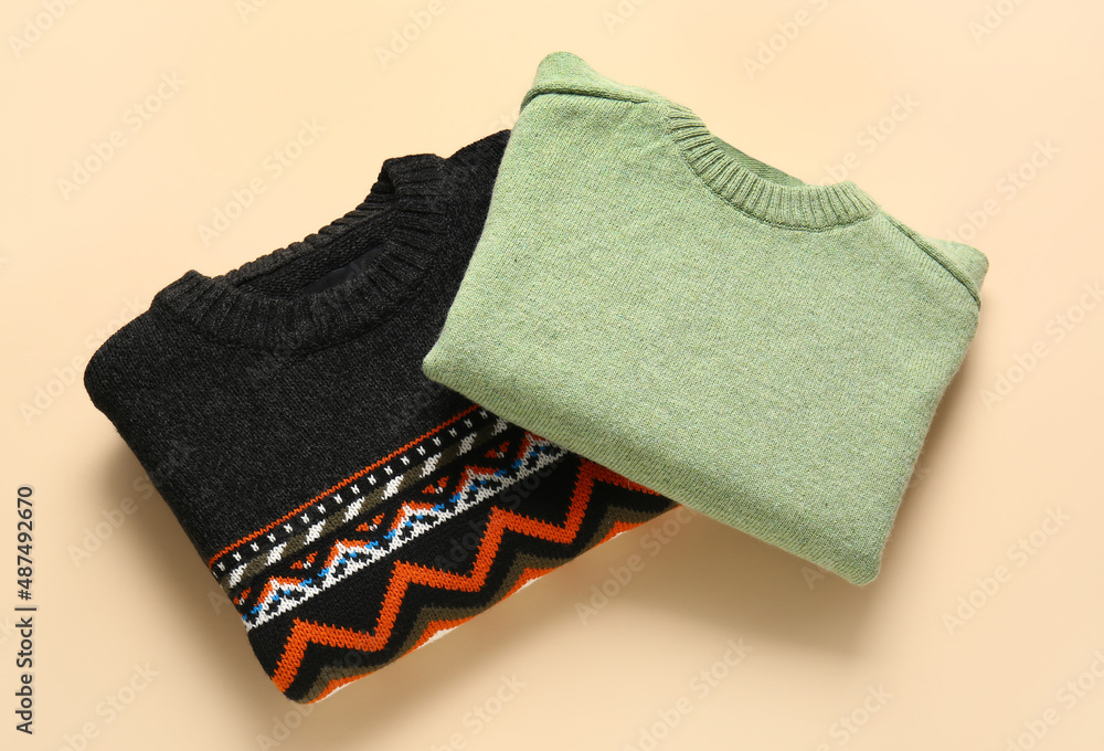 Different stylish sweaters on color background