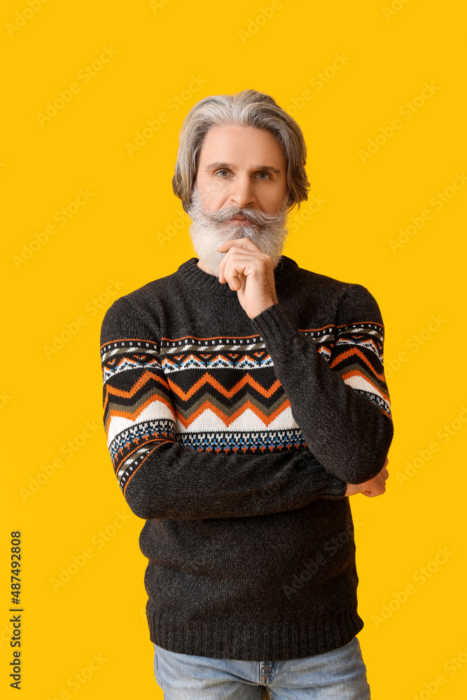 Handsome senior man in knitted sweater on yellow background