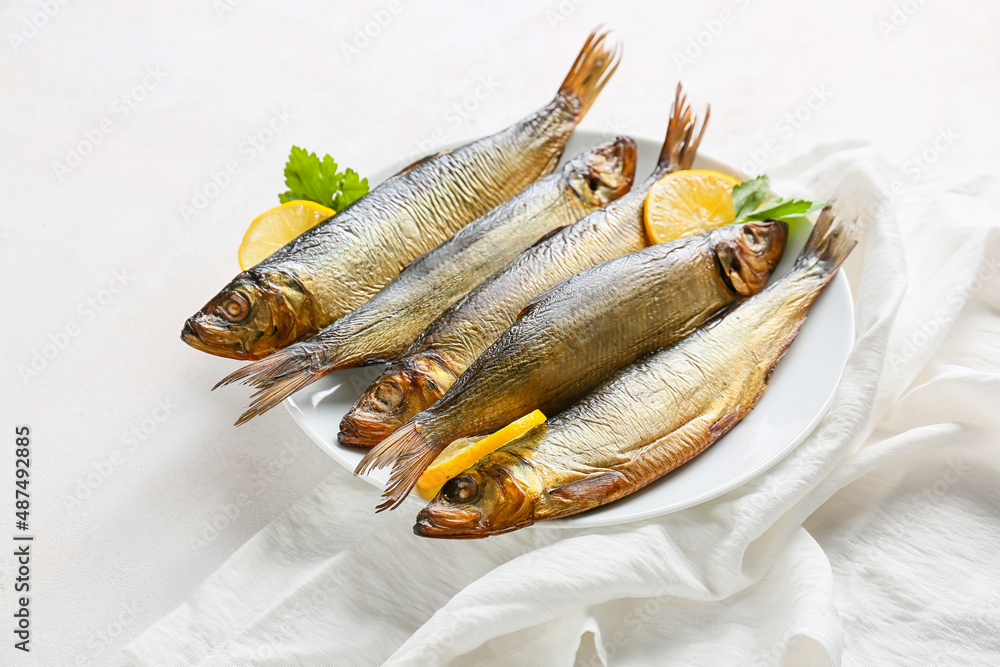 Plate with smoked herring fishes on white background