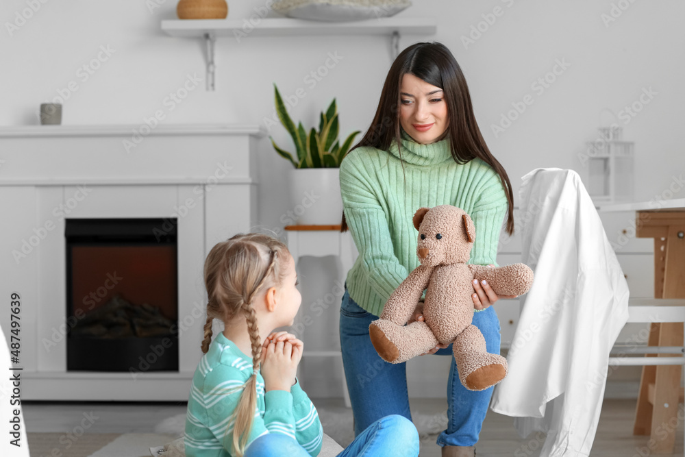 Happy mother giving toy to her little daughter at home