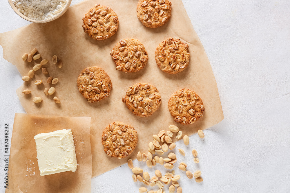 Parchment paper with tasty peanut cookies and butter on white background