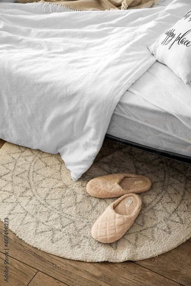 Slippers near bed in modern room