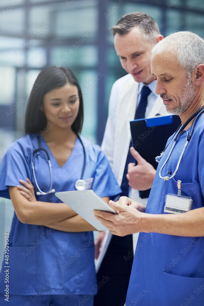 These are some promising results. Shot of a group of doctors talking together over a digital tablet 