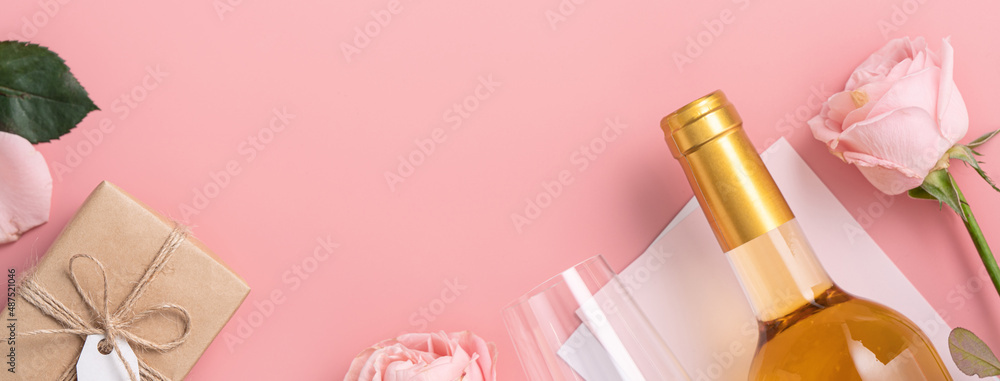 Valentines Day gift with wine and pink rose bouquet on pink background.