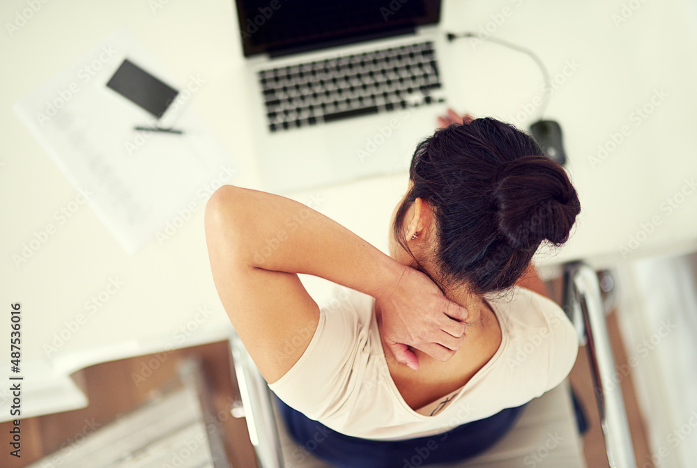 Sitting for too long takes its toll on spine. High angle shot of a young businesswoman holding her n