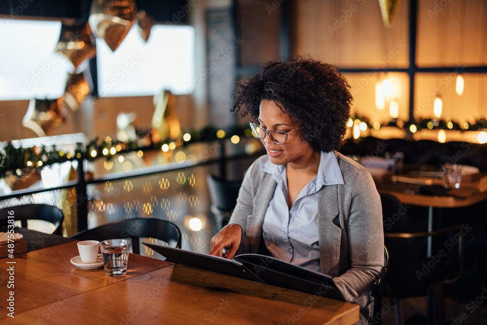 Concentrated African-American woman, tracing her finger across the menu.