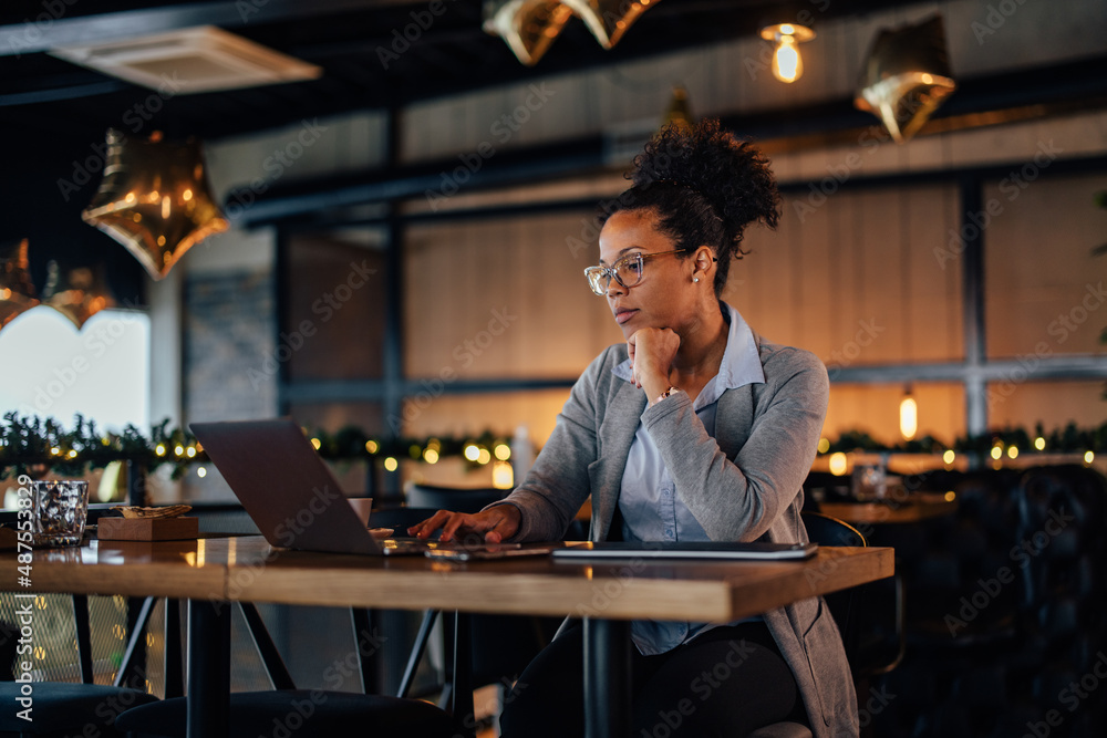 Concentrated African-American woman with a ponytail, working as a restaurant manager.