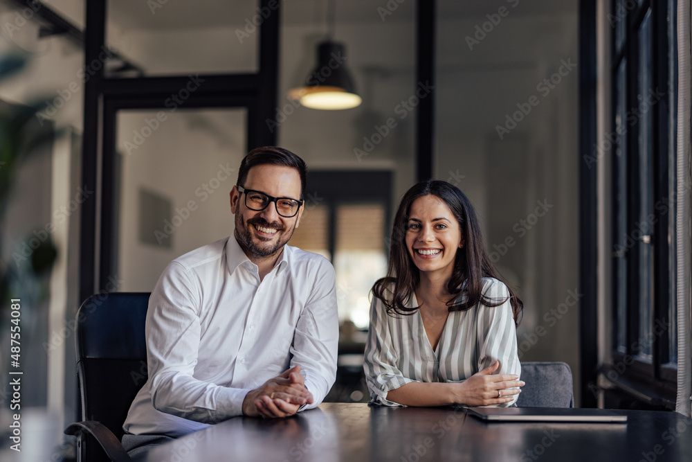 Portrait of happy business partners, smiling for the camera in the office.