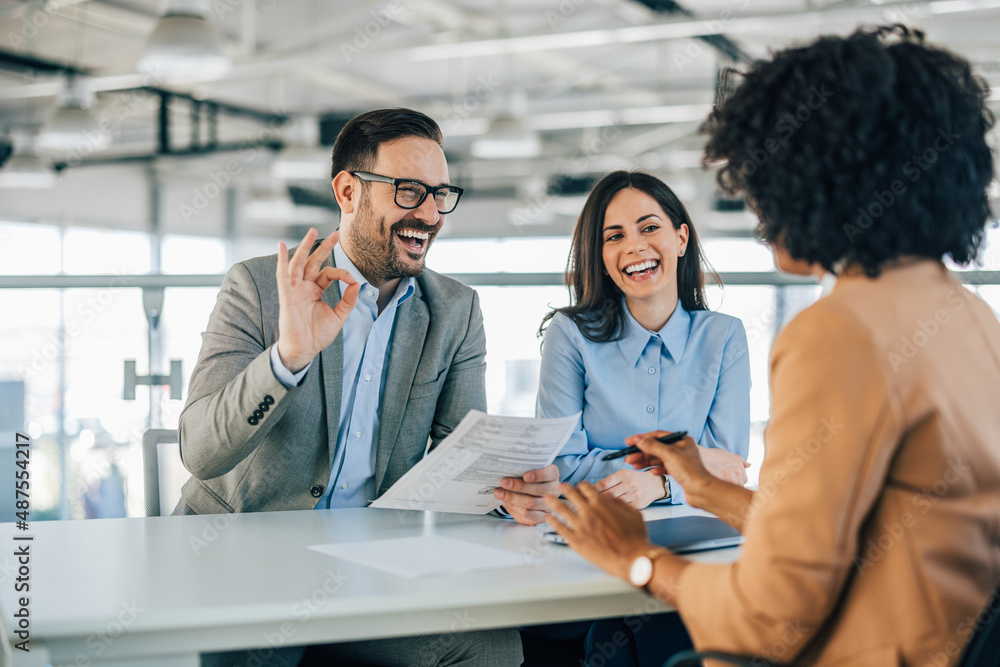 Smiling businessman, agreeing with a female customer, holding a contract.