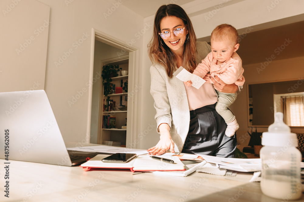 Mom holding her baby while working in her home office