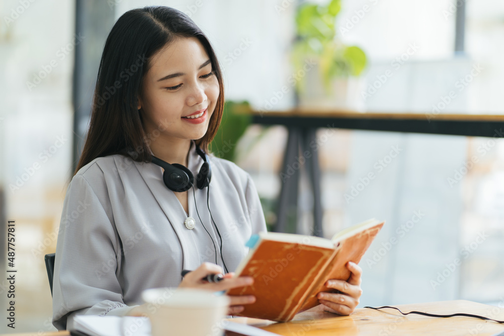 年轻的亚洲女性在日记中记笔记。女大学生在为考试做笔记