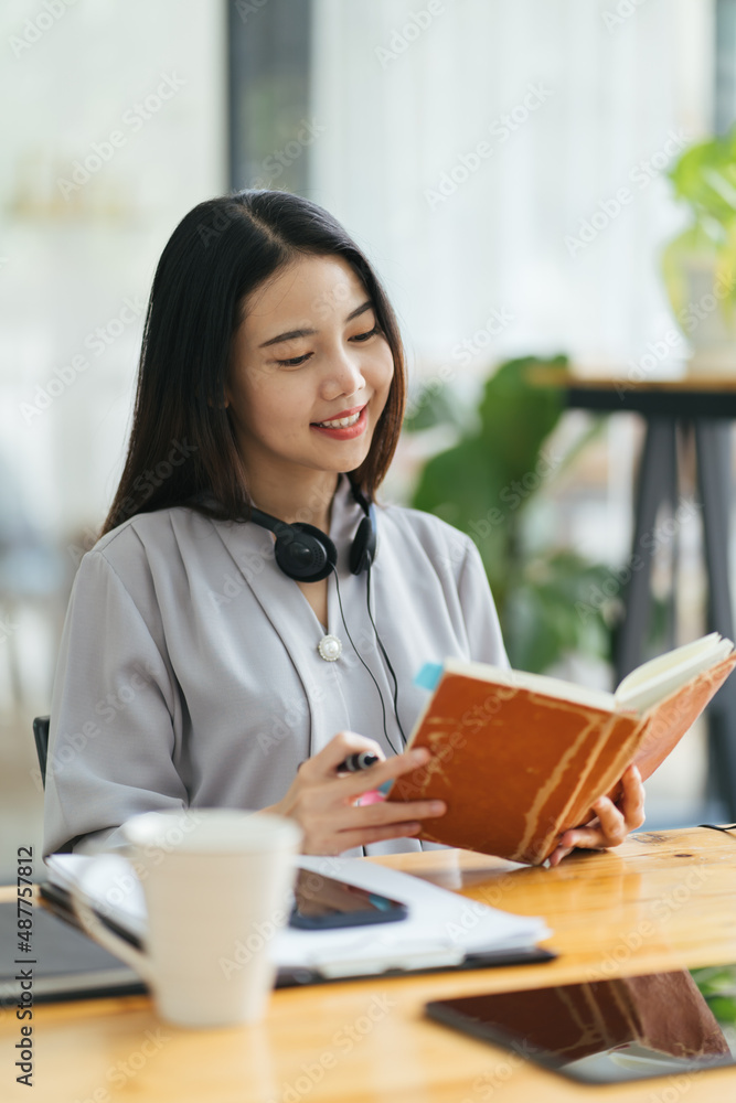 Young asian woman taking down notes in diary. Female university student preparing note for the exam 