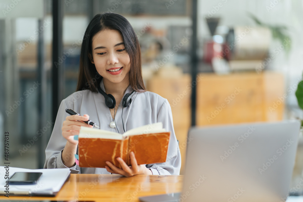 年轻的亚洲女性在日记中记笔记。女大学生在为考试做笔记